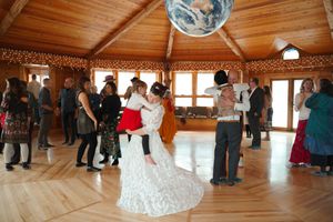 Wide view of a dance floor in a wooden lodge where couples are dancing at a formal event.