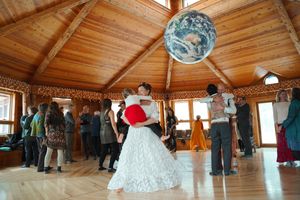 Panoramic view of a wooden dance floor with partygoers celebrating under warm string lights.