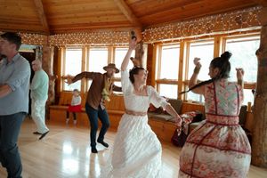 Wedding celebration underway in a spacious wooden venue with large windows and festive lighting.