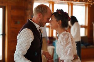 Dancing pairs fill a sunlit wooden reception hall during a wedding celebration.