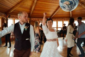 Couple dancing together in a rustic wooden venue decorated with twinkling lights and wooden beams.