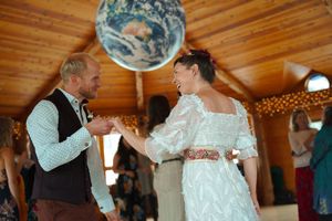 Dancers move together beneath a decorative globe and string lights in a wooden-beamed room.