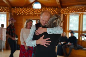 An emotional embrace during a celebration in a wooden room with string lights.