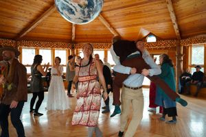 Wedding reception dance floor in a wooden lodge with natural light streaming through windows.