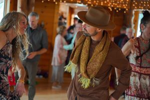 Dancers in western attire enjoying a lively moment at an indoor venue decorated with string lights.