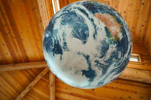 A large illuminated Earth globe hangs from wooden beams in an octagonal ceiling.