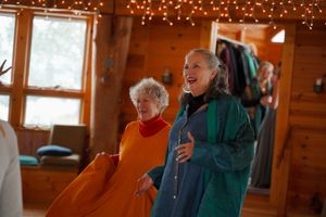 Two people dancing in a rustic wooden room decorated with string lights and paper lanterns.