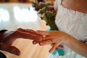 Close-up of hands exchanging rings during a wedding ceremony with soft lighting.