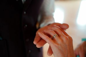 Close-up shot of hands with elegant wedding rings in natural lighting.