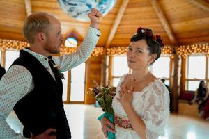 Wedding couple sharing a playful moment under decorative lights in a wooden reception venue.