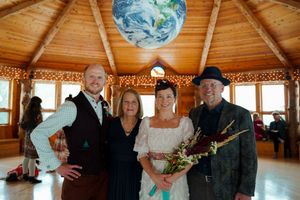 Group dancing and celebrating in a rustic log cabin venue with twinkling lights and decorative globe lanterns.