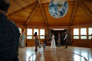 People gather in a wooden circular room with a blue earth globe hanging from the ceiling.