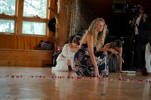People gathering in a rustic wooden room with string lights and a circle of rose petals on the floor.
