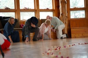 Children crawl on a wooden dance floor decorated with scattered rose petals.