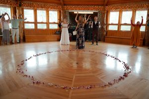 A wooden octagonal room with windows and a circle of rose petals arranged on the hardwood floor.