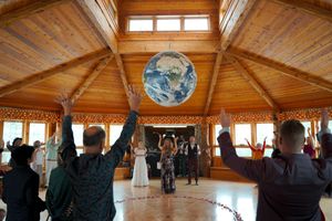 Panoramic view of a wooden lodge interior with exposed beams and large windows during a group session.
