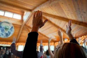 Guests raising their hands in celebration inside a rustic wooden venue with vaulted ceilings.
