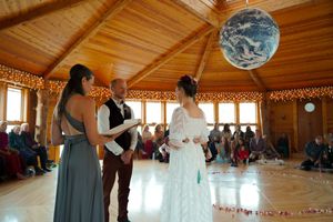 A panoramic view of a rustic wooden wedding venue decorated with hanging lights and white fabric.