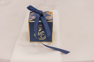 White gift box with navy blue ribbon and gold decorative details.