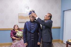 Person being helped with formal attire preparations in an indoor setting.