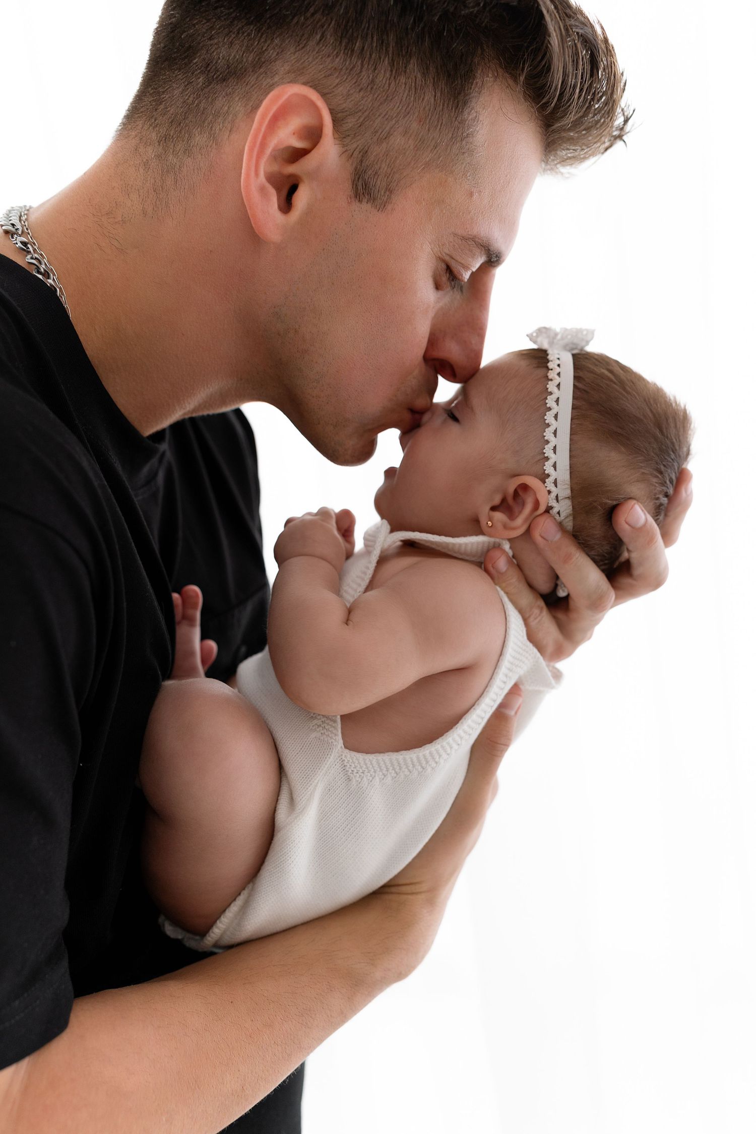 Tender moment captured between parent and infant in black and white portrait.