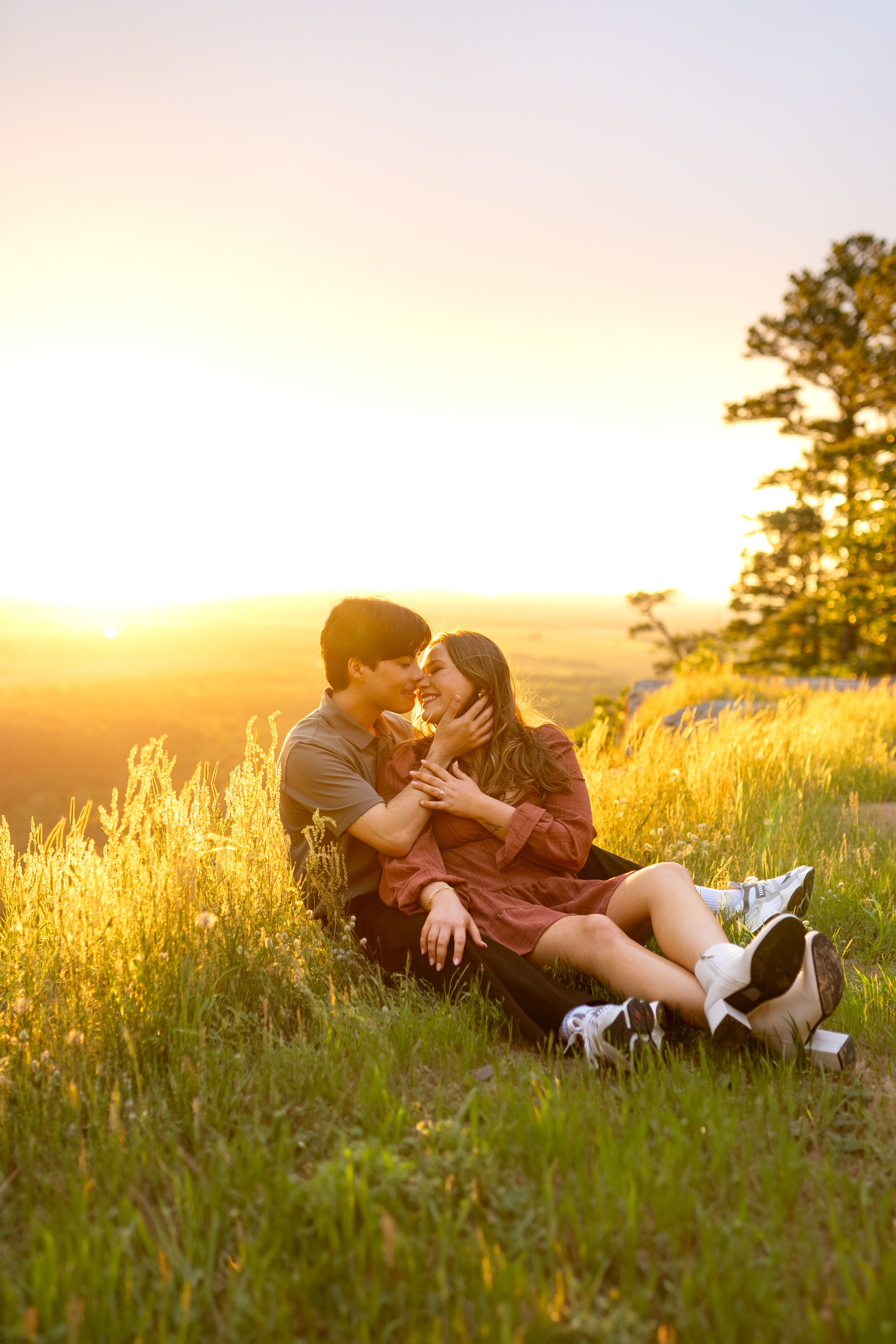Couple lying in golden grass during sunset sharing an intimate moment amongst wildflowers.