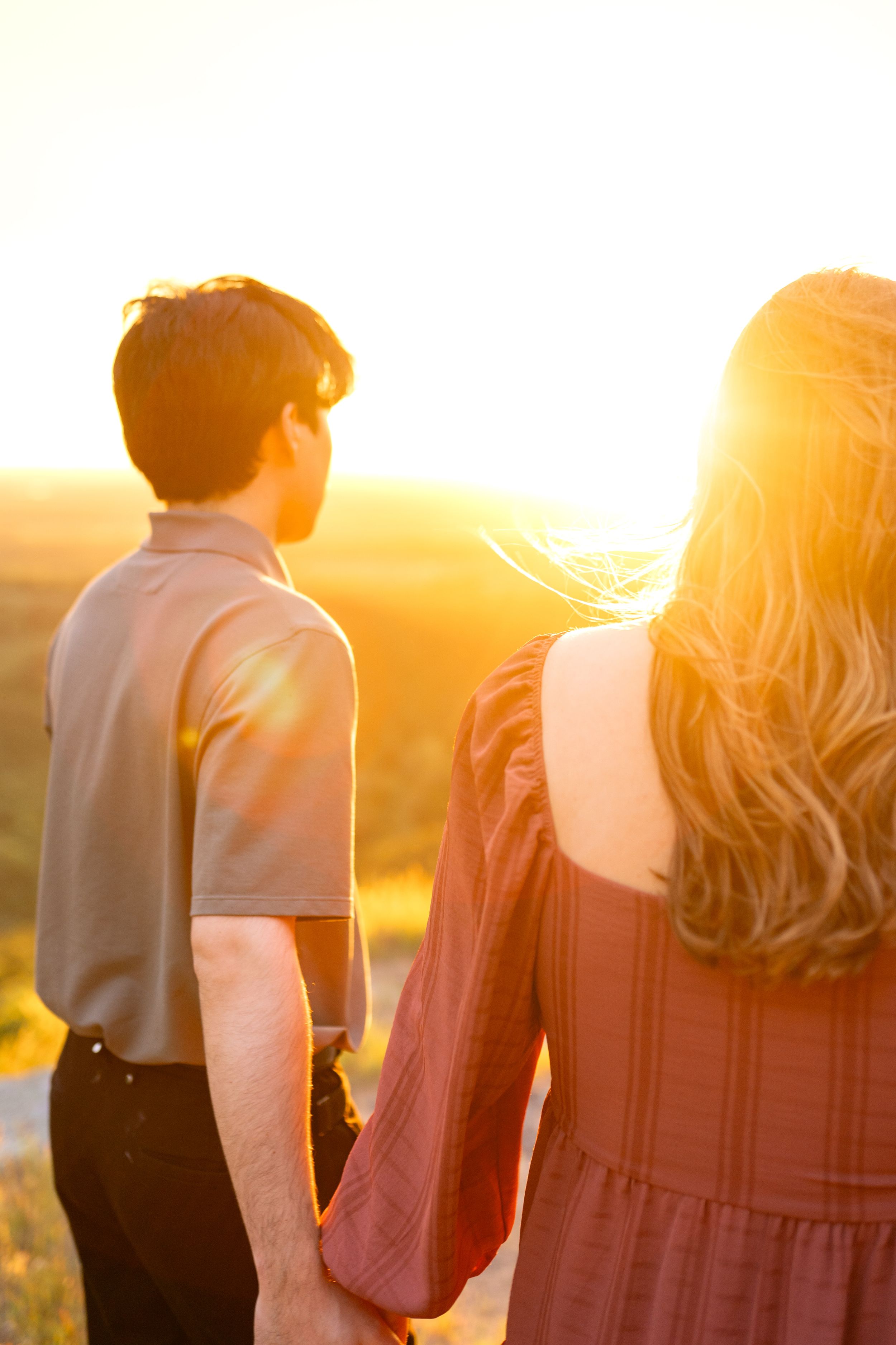 Silhouettes of two people standing together against a warm sunset backdrop.