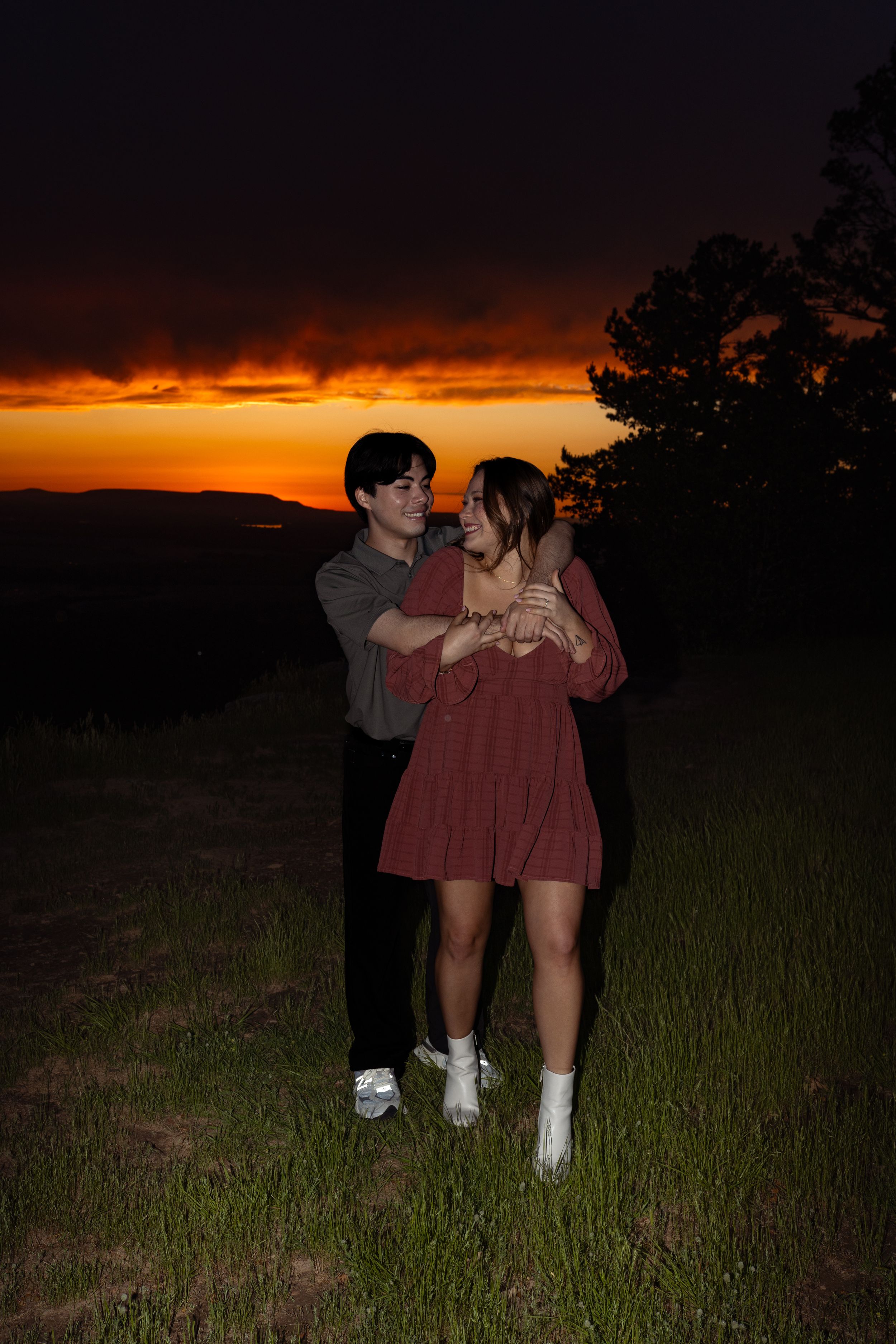 Two people share a romantic moment on a hillside as the sun sets.