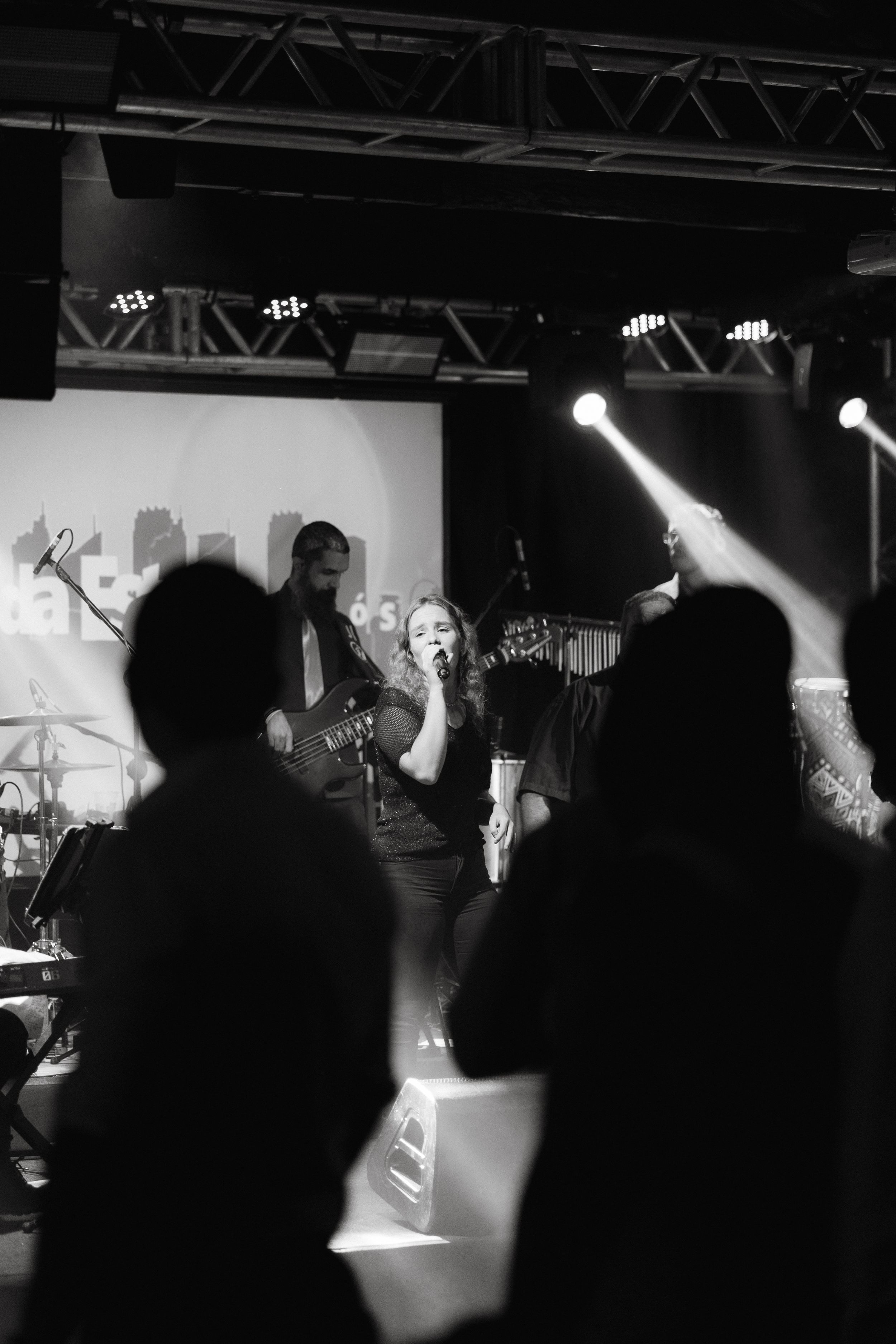 Silhouettes of concert audience standing in front of a stage with lighting equipment.
