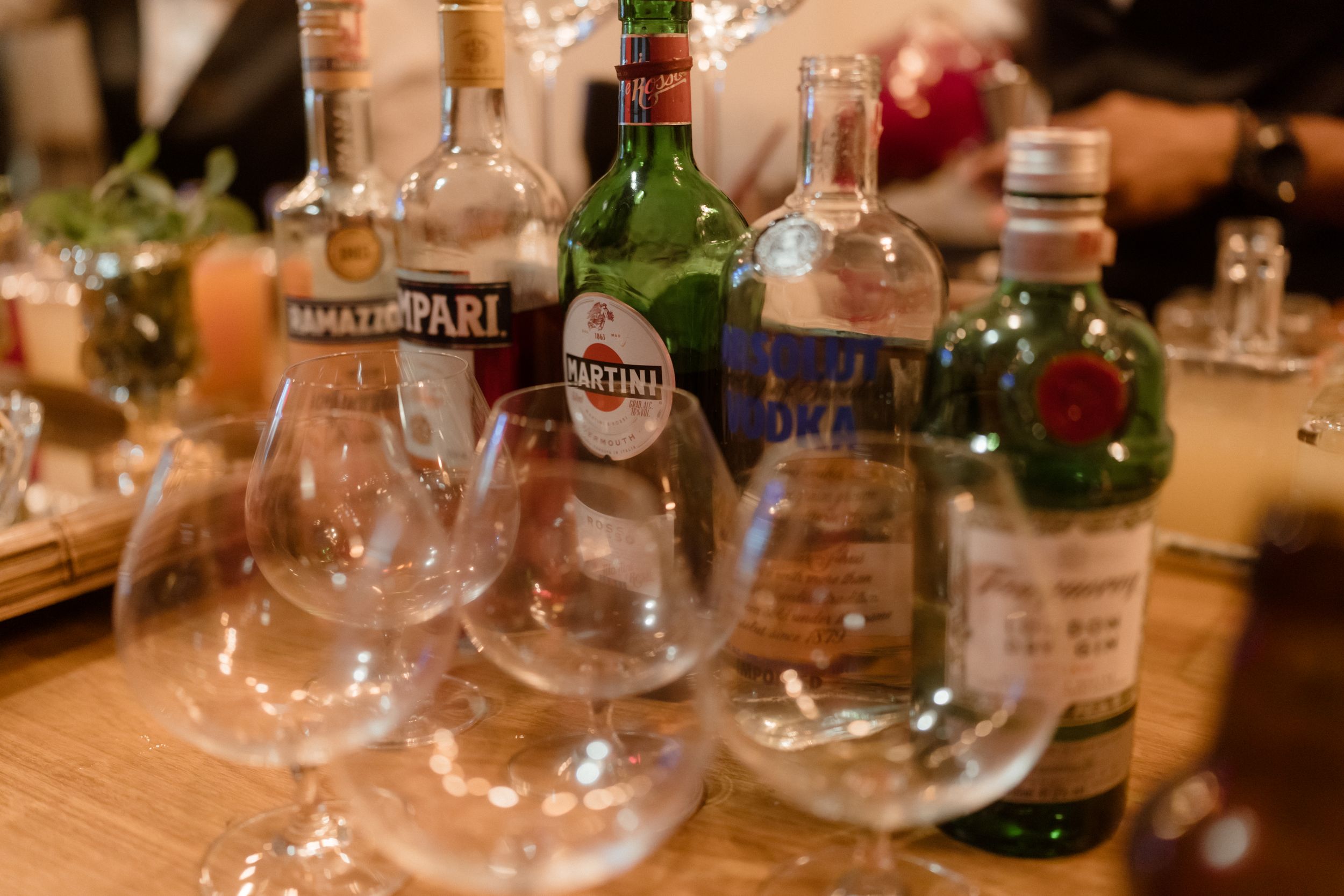 Row of wine glasses and bottles arranged on a wooden table.