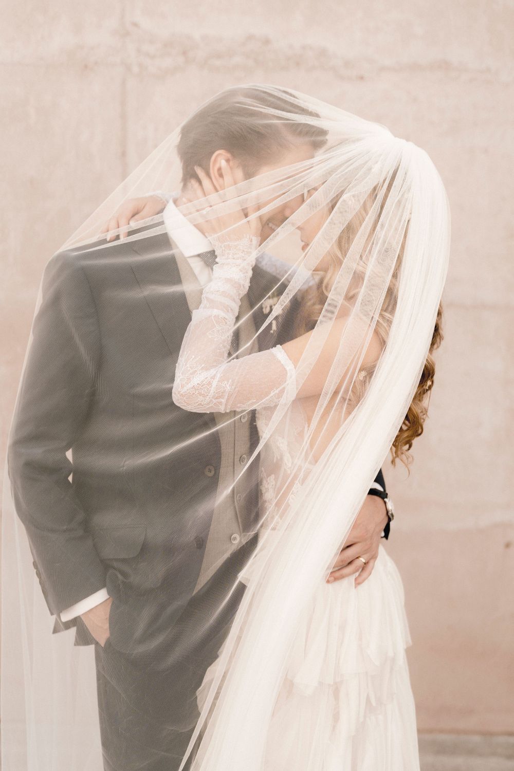 Romantic sequence showing couple embracing behind flowing bridal veil in soft focus.