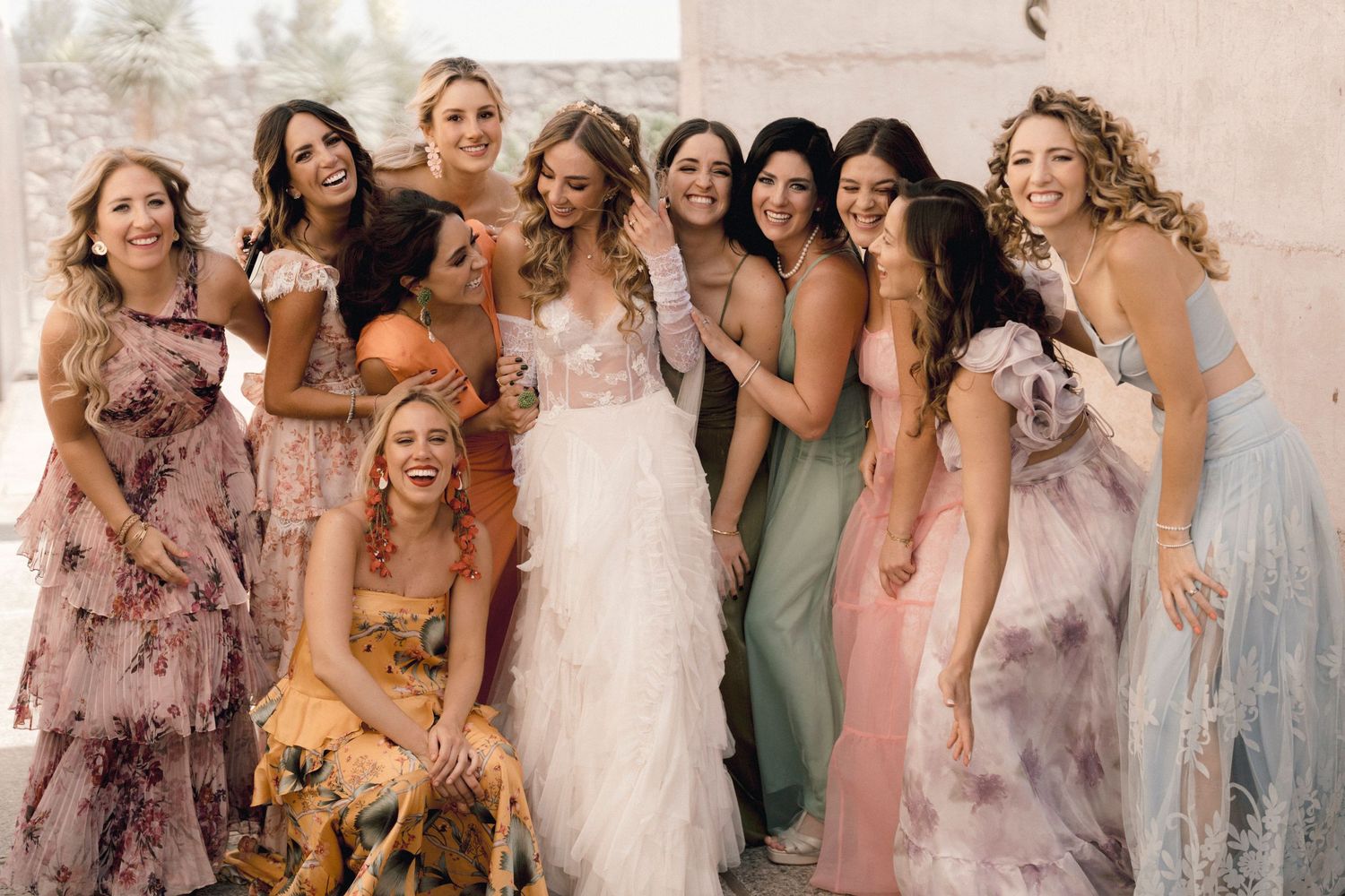 Wedding party group photo showing bridesmaids in pastel dresses celebrating with bride.