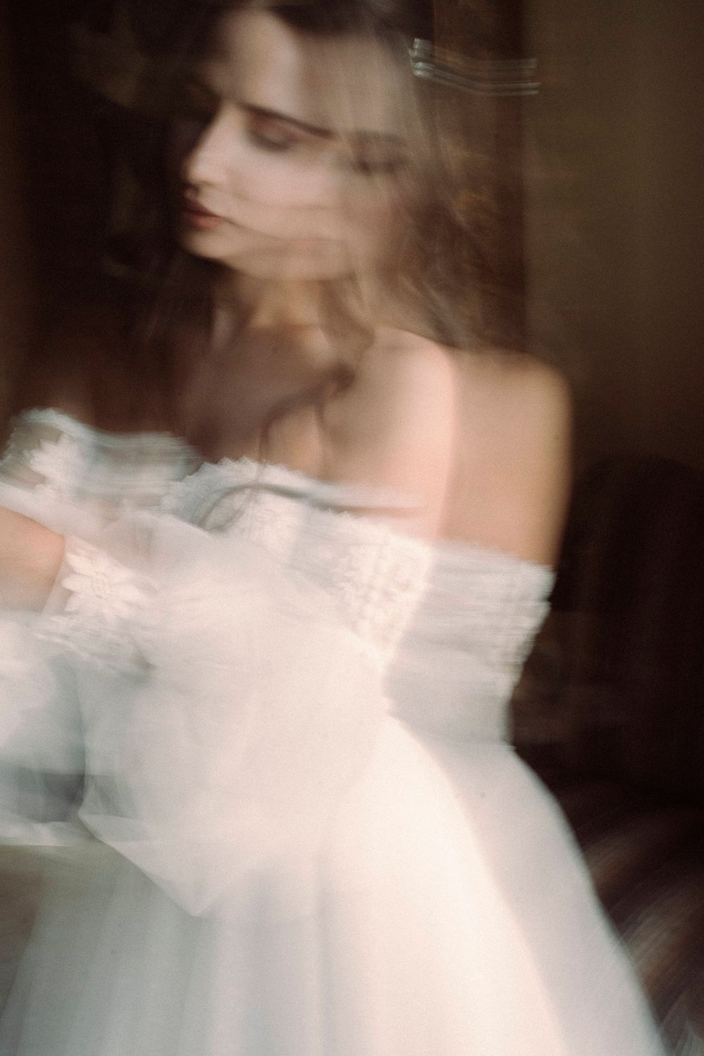 A blurred artistic motion portrait sequence showing ethereal movement in white dress against dark background.