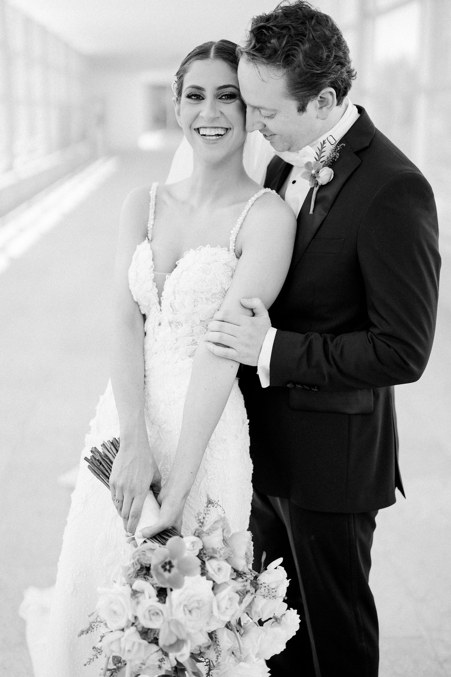 Elegant wedding couple sharing an intimate moment with a beautiful bouquet of light pink roses.
