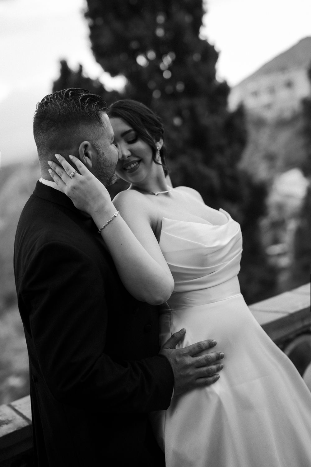 Black and white wedding photograph sequence showing a romantic kiss between newlyweds outdoors.