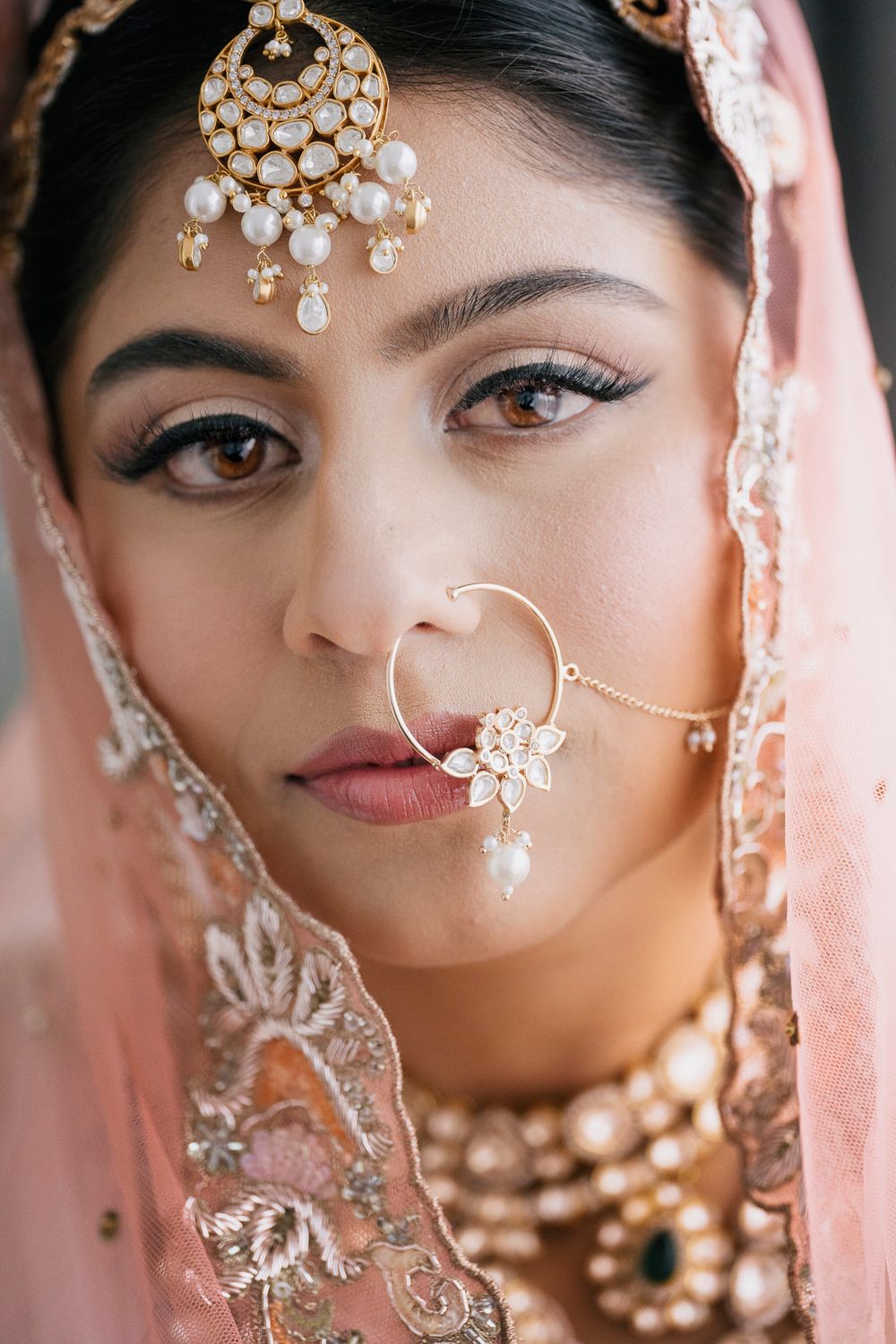 Traditional Indian bridal jewelry and makeup details shown in a series of close-up portraits with delicate gold accessories.