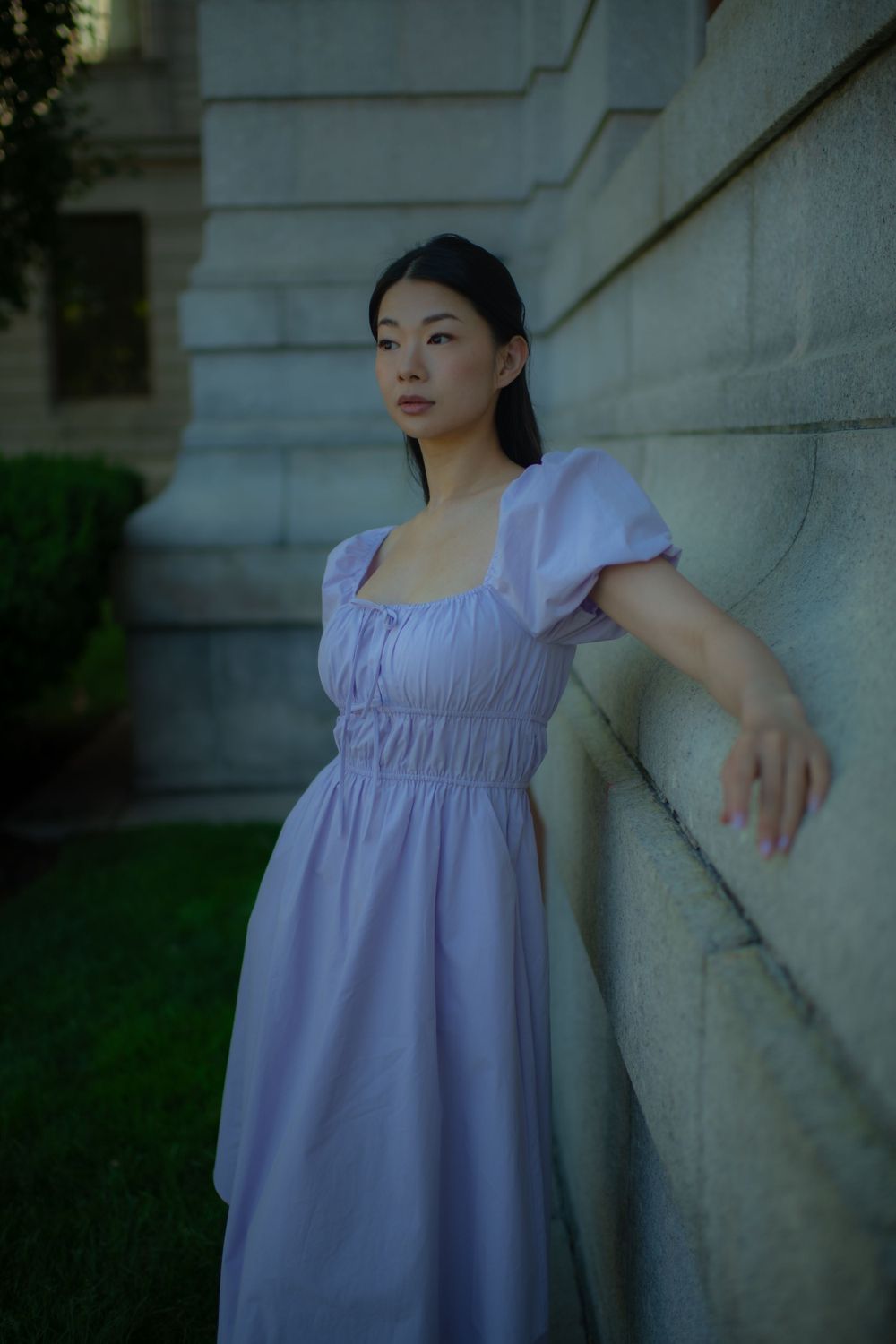 Artistic portrait against a stone wall featuring a lavender regency-style dress with puff sleeves.