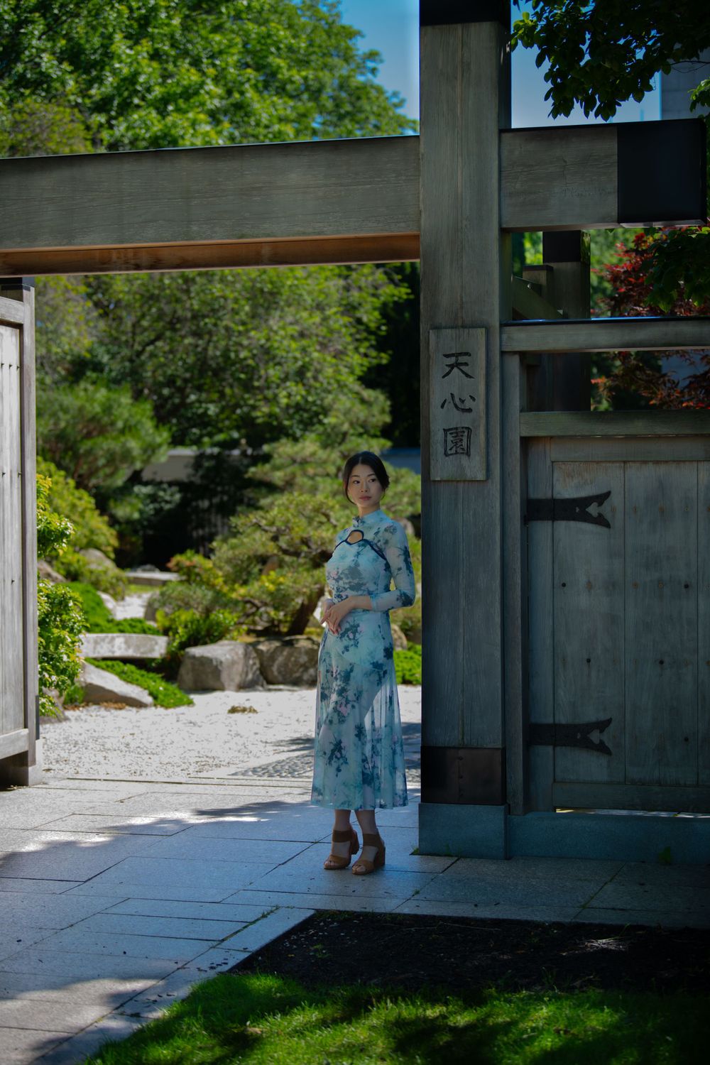 A traditional Japanese garden setting with stone path and wooden gate featuring a blue patterned dress.