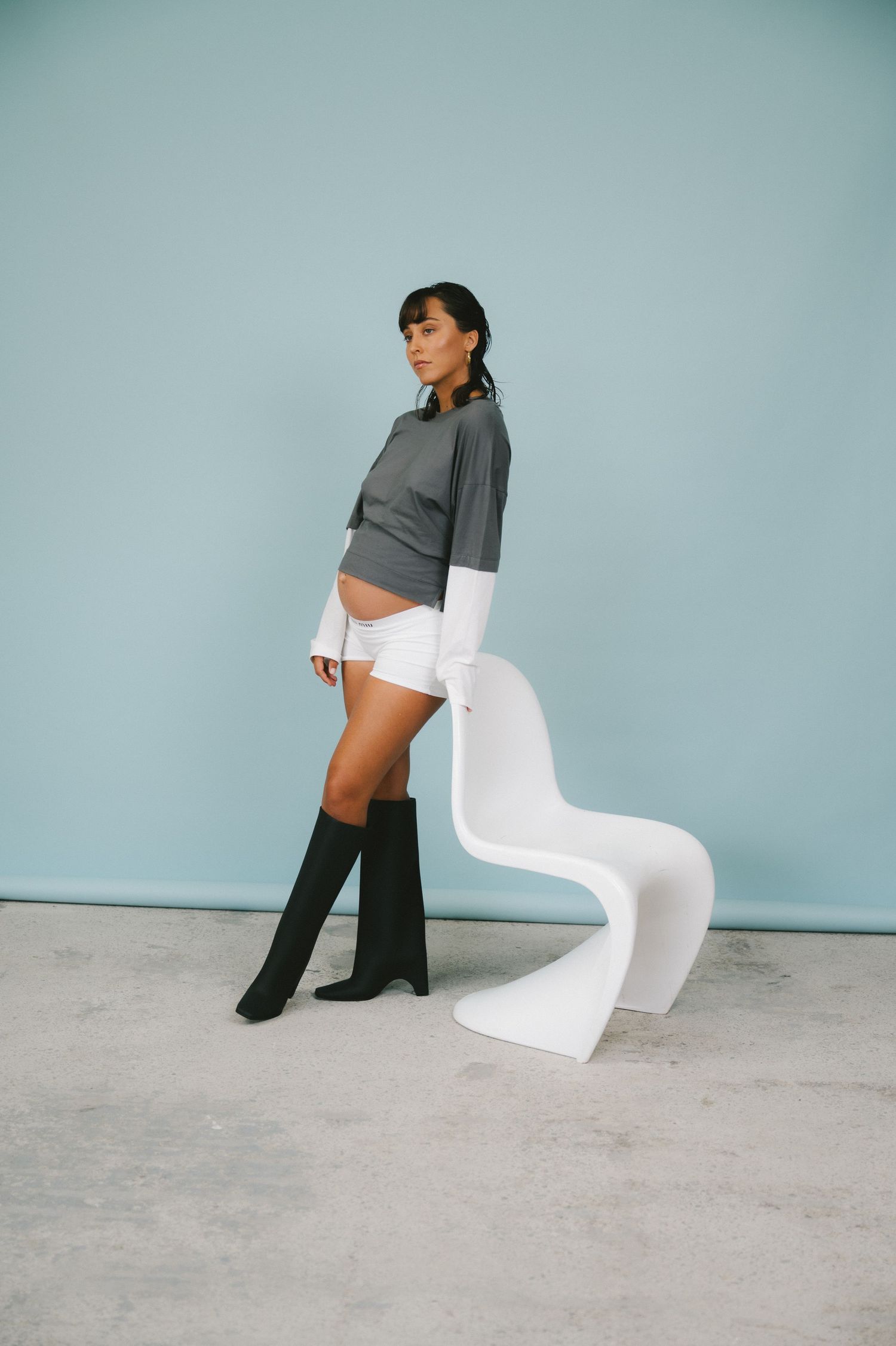 Creative fashion editorial series showcases white chair alongside modern styling with dark boots.