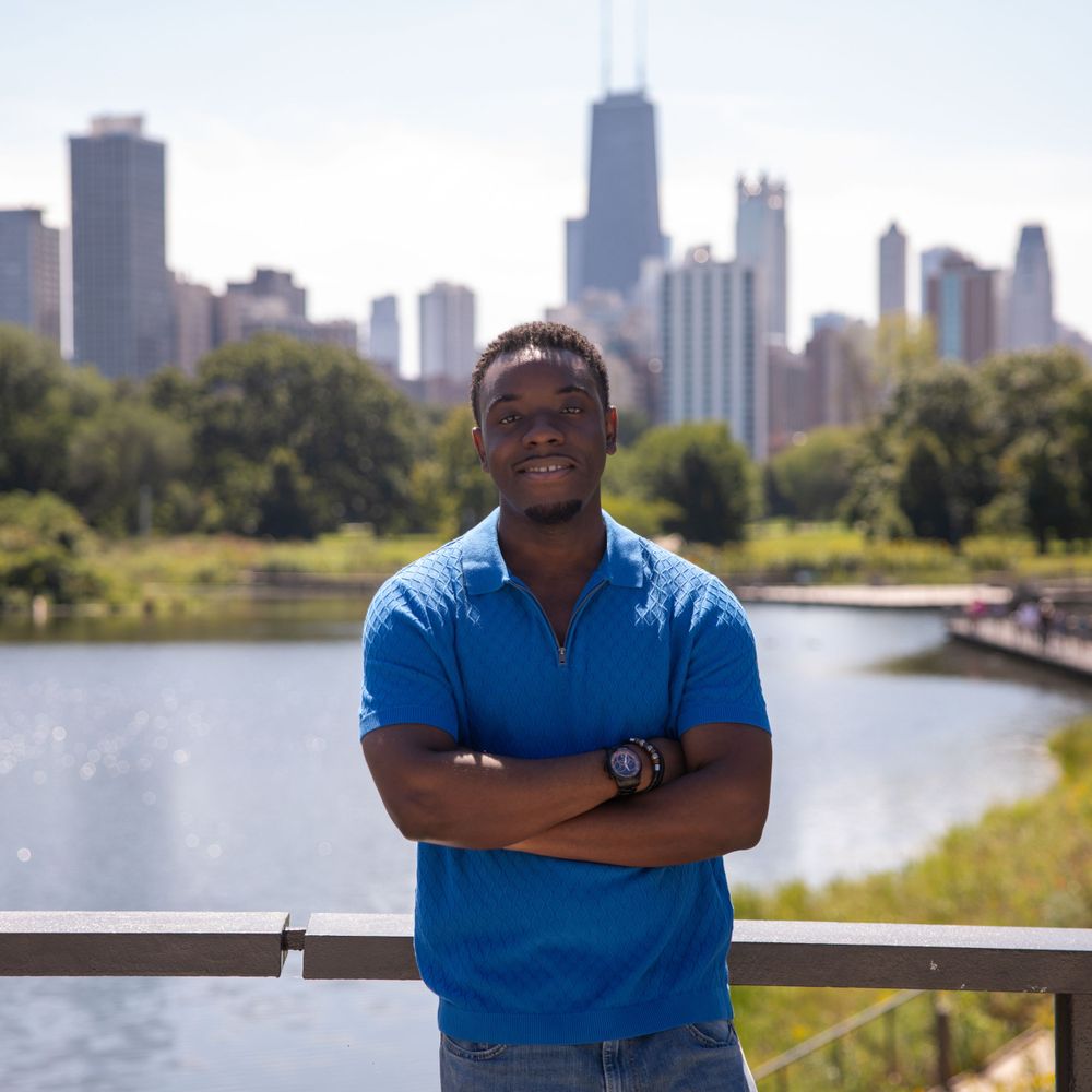 A photo captured against the Chicago skyline at Lincoln Park with a person in a blue polo shirt smiling.