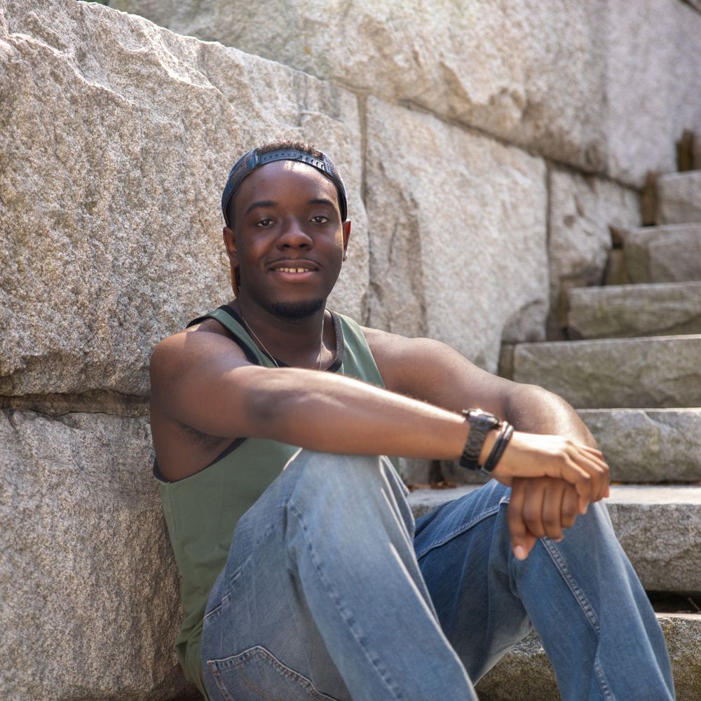 Casual portrait on stone steps with someone wearing a tank top and jeans.