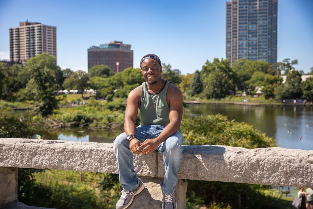 Scenic photo by a lake in an urban park with high-rise buildings visible in the background.