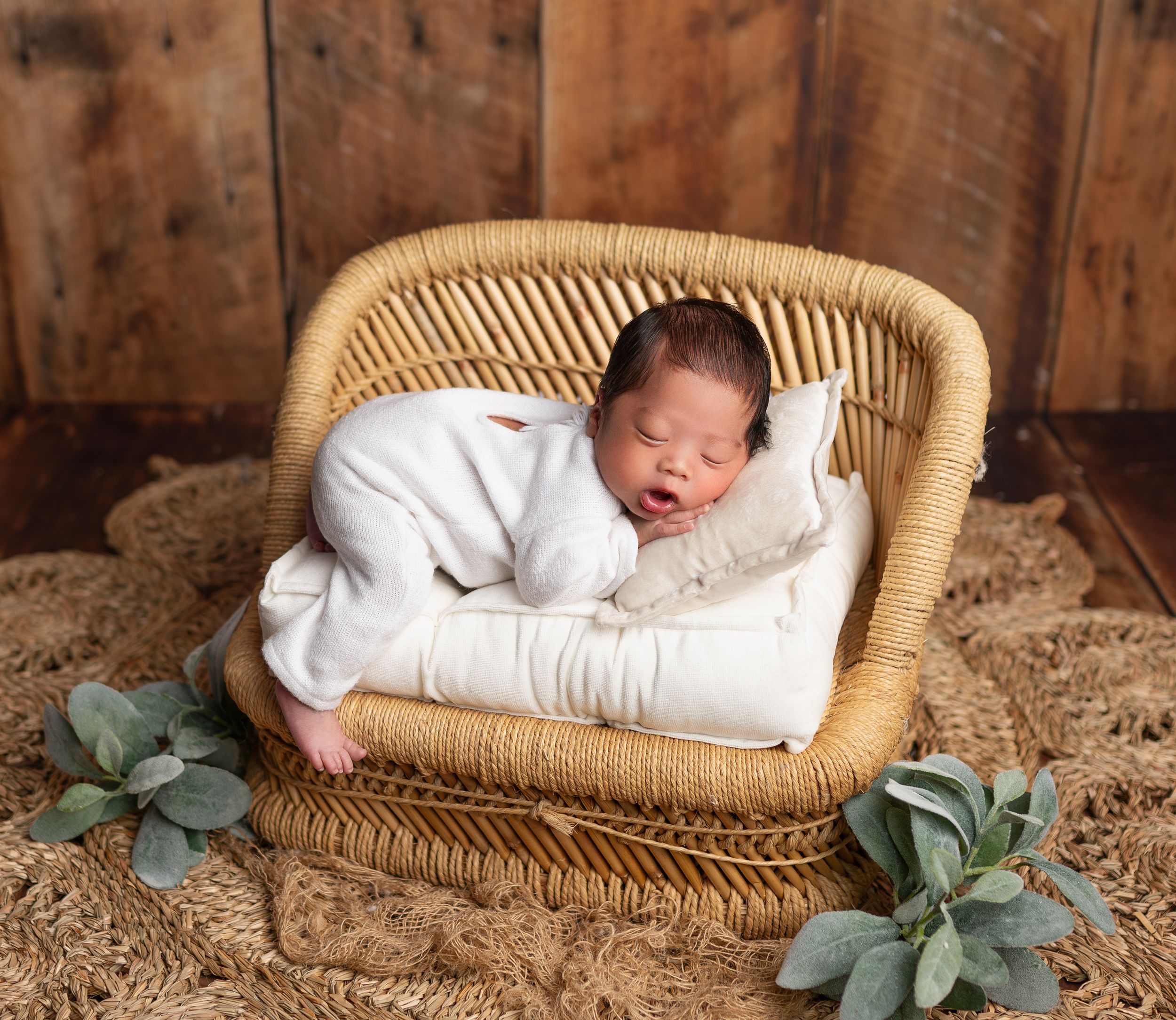 Cozy newborn photography in Brooklyn, NY, featuring a sleeping baby nestled in a wicker basket with warm, rustic textures.