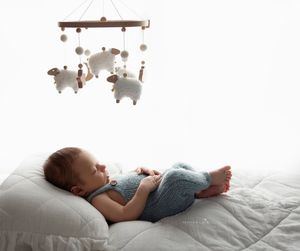 Newborn baby boy in knitted blue outfit posed on  white backlit background, Brooklyn NYC newborn photographer.