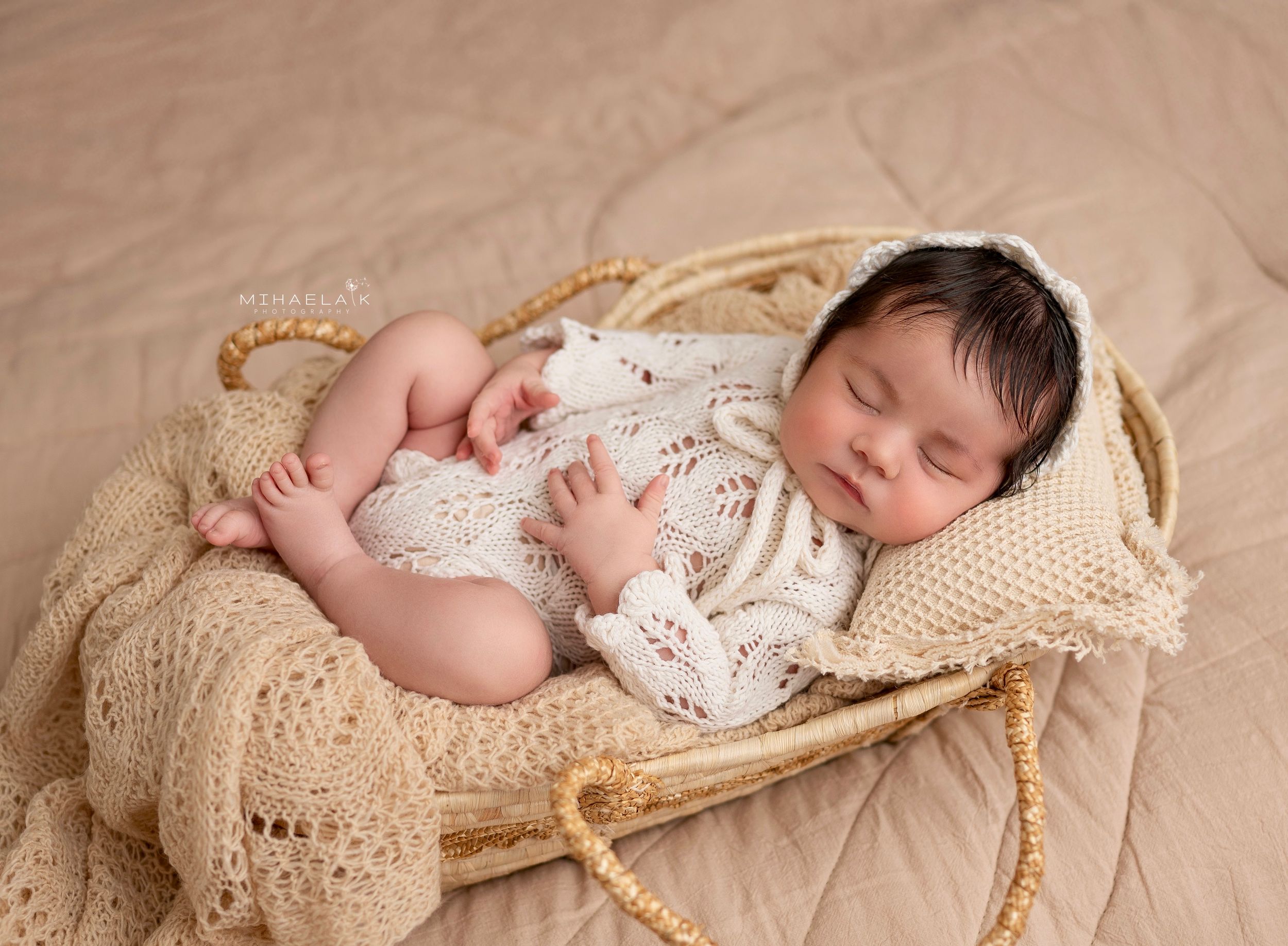 Newborn baby in white knit romper and  bonnet. Brooklyn NYC baby photography.