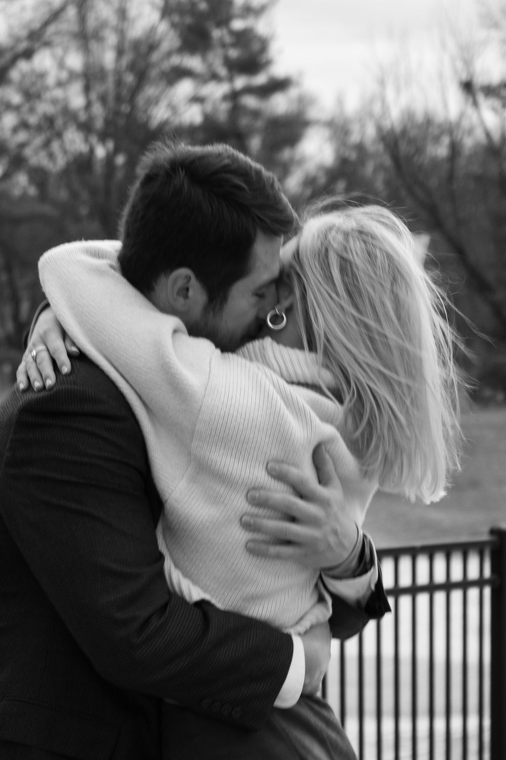 A romantic black and white photo of a couple embracing outdoors.