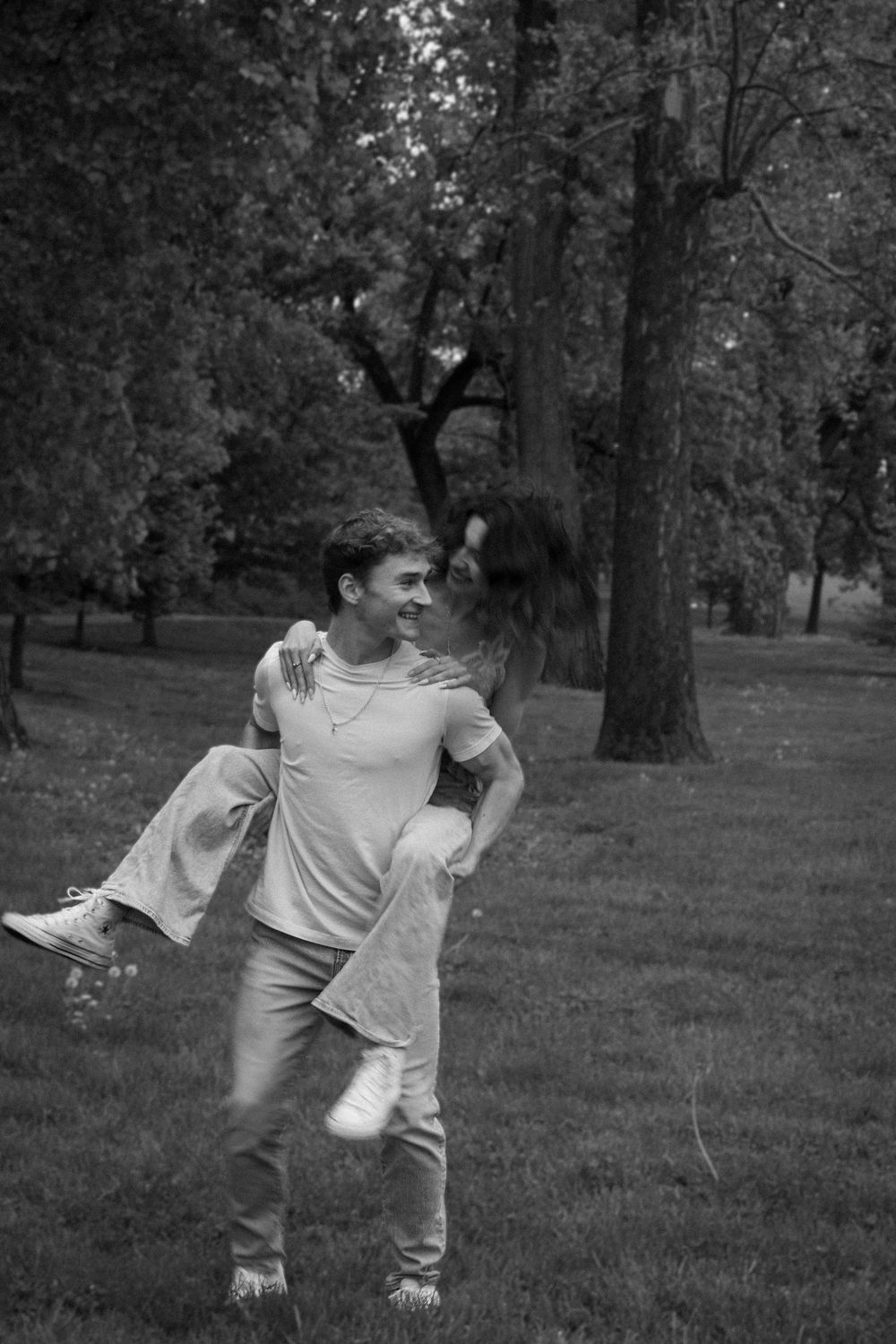 Black and white photo series of couple dancing playfully in a park.