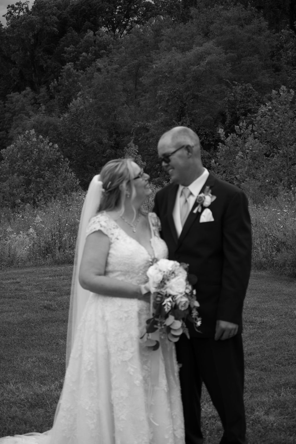 A wedding couple shares an intimate moment outdoors in black and white photography.