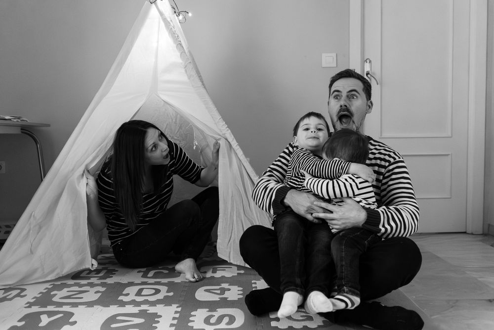 Black and white portrait of family relaxing by teepee tent. Photographe de famille fotógrafa de familia sevilla fotógrafo de la vida real