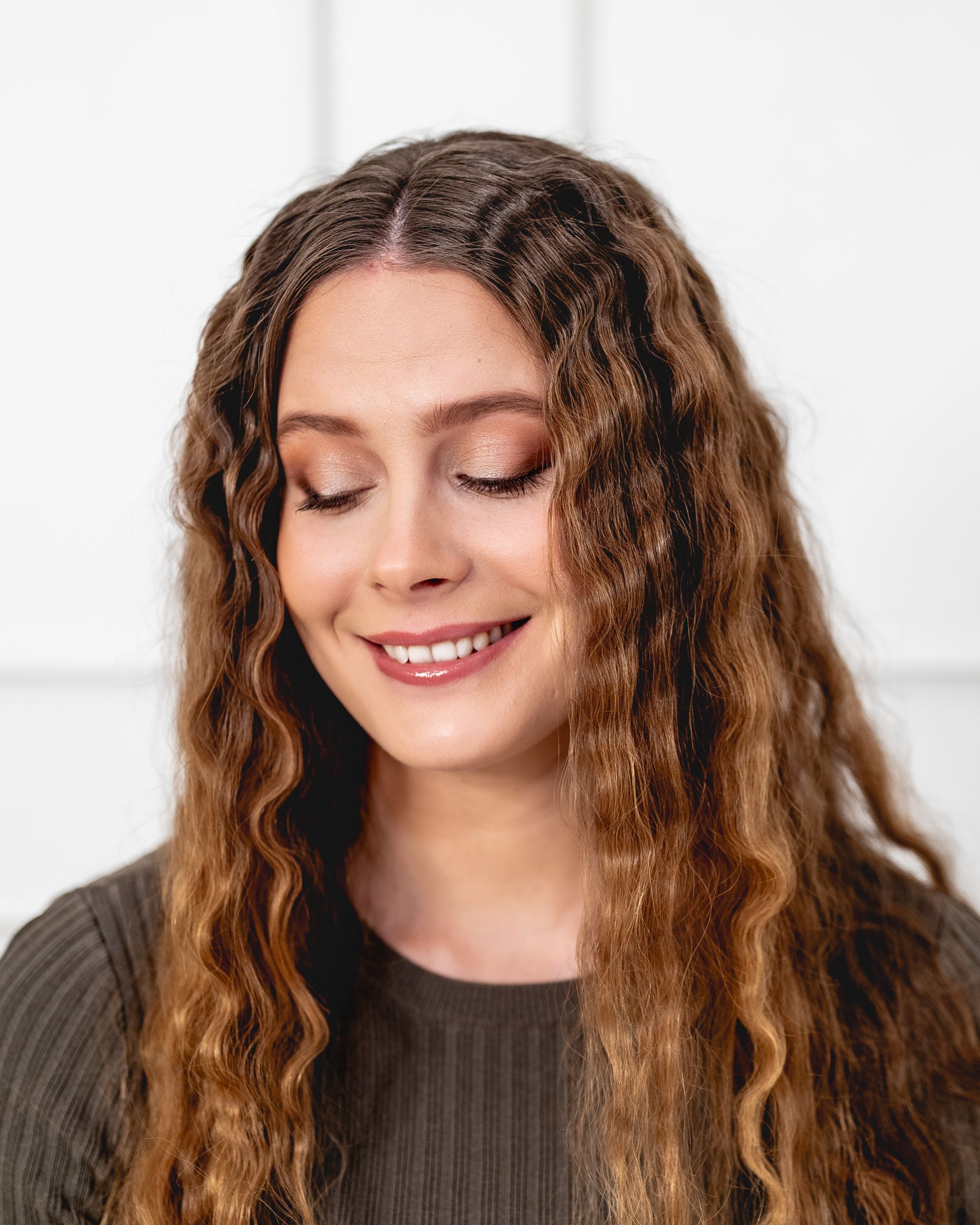 Beauty portrait of person with wavy brown hair and natural makeup.